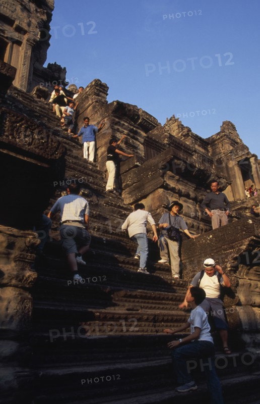 CAMBODIA, Siem Reap Province, Angkor Wat, Tourists climbing steep narrow steps to upper or third level.