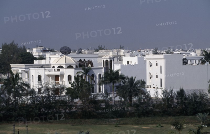 OMAN, Muscat, White painted housing amongst palms.