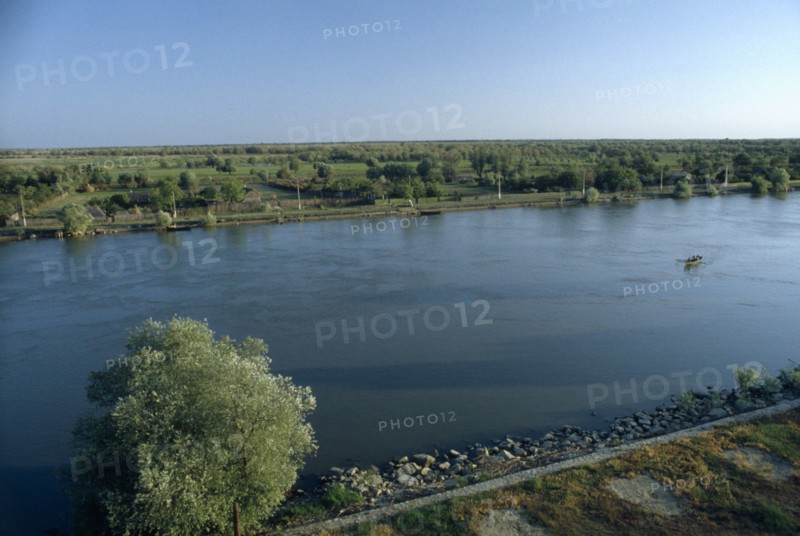 ROMANIA, Danube Delta, "Small rowing boat on the River Danube through flat, tree covered landscape."
