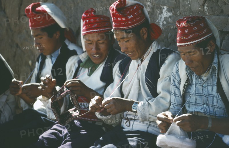 PERU, Puno, Lake Titicaca, Taquile Island.  Line of men knitting.