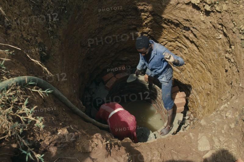 UGANDA, Aid, Trainee woman brick layer lining newly dug well near Jinja for project funded by Comic Relief.