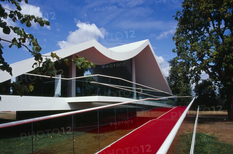 ENGLAND, London, Kensington Gardens.  The Serpentine Gallery Pavilion designed by architect Oscar Niemeyer.  Exterior part framed by trees.