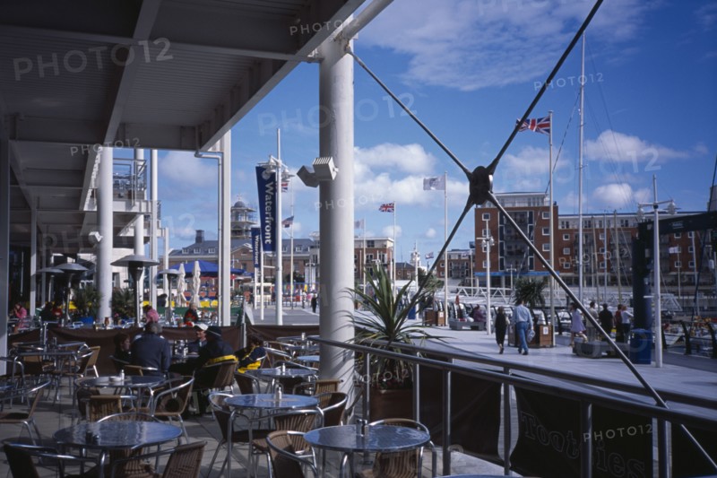 20059200 ENGLAND Hampshire Portsmouth Gunwharf Quay Shopping Centre. Outside Cafe with view across table and chairs and exterior structures.