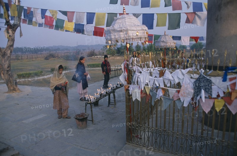 NEPAL, Lumbini, Pilgrims in front of the Ashoka pillar dating about 320 BC beside pond at sacred site where Buddha was born.