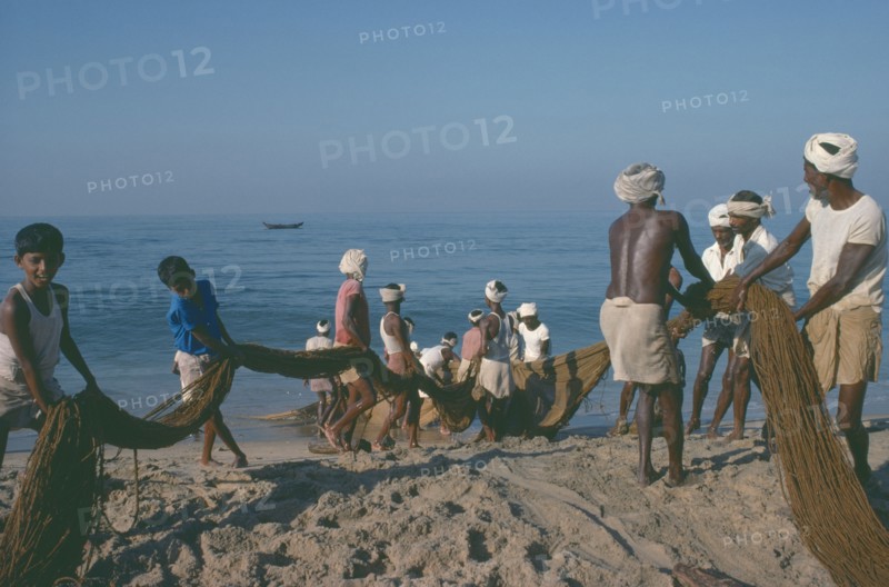 INDIA, Kerala, Kovalam, Fishermen on beach pulling in nets.