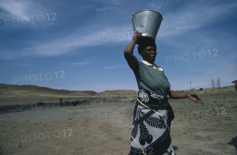 LESOTHO, Water, Woman carrying water from well on her head.