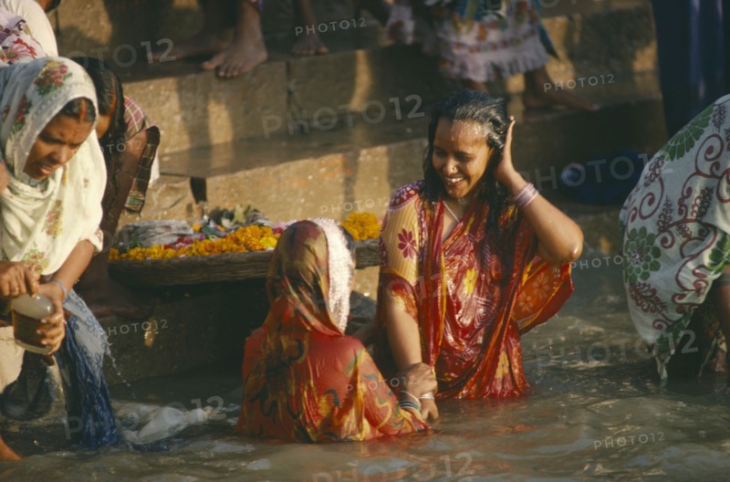 INDIA, Uttar Pradesh, Varanasi, Women wearing saris bathing in the sacred ghats on the River ganges.