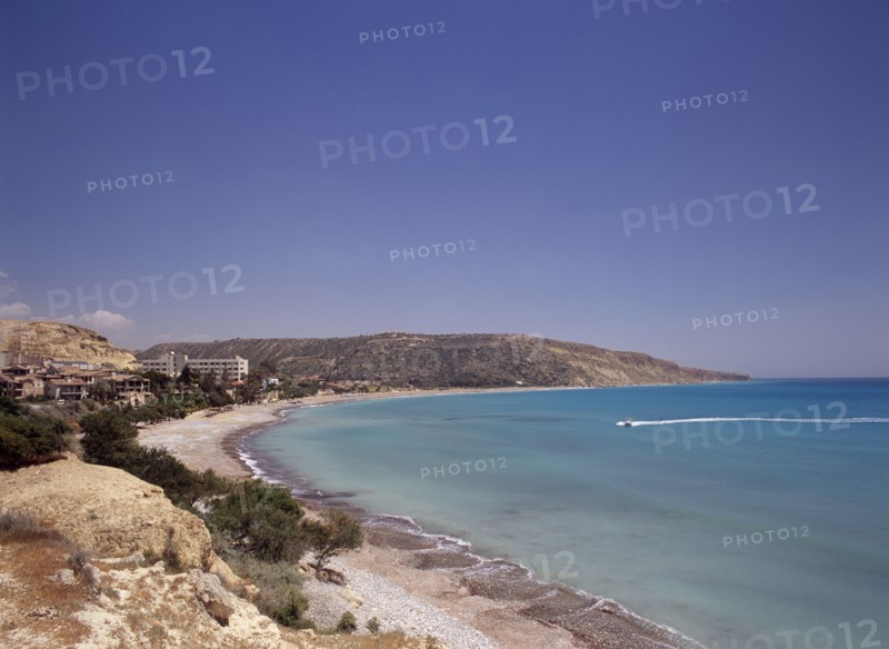 CYPRUS, Pissouri, Water skier and speed boat in Pissouri Bay encircled by quiet beach with surrounding rocky coastline overlooked by hotel and other buildings.
