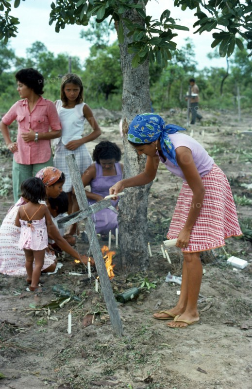 BRAZIL, Sao Paulo, Ribeirao Bonito, Catholic family conducting memorial service around makeshift grave in slum area graveyard.
