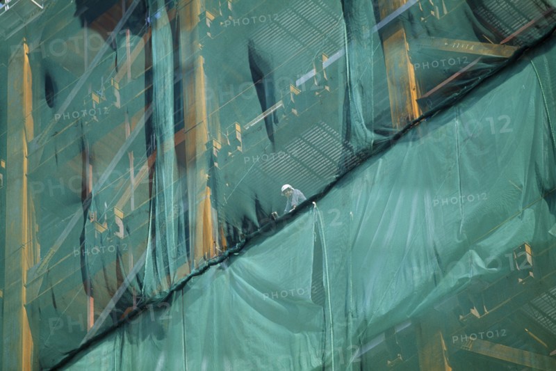 JAPAN, Shinjuku, Tokyo, Construction worker looking out from skyscraper safety netting.
