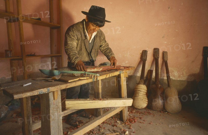 BOLIVIA, Chuquisaca, Tarabuco, Charango musical instrument maker at workbench.