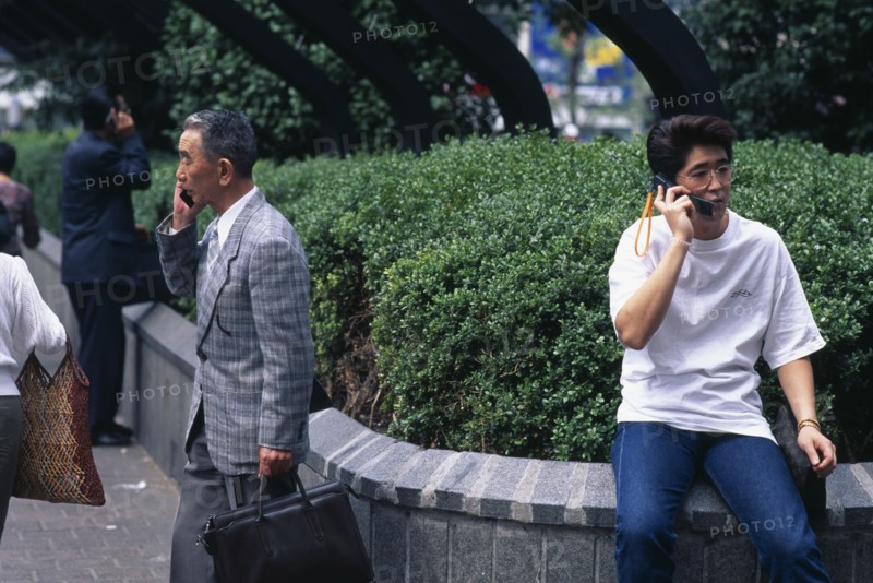 JAPAN, Shibuya, Tokyo, Three men ranging in age talking on mobile phones.