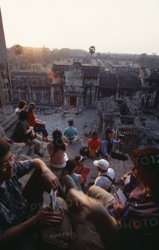 CAMBODIA, Siem Reap Province, Angkor Wat, Tourists with cameras watching the sunset from the central sanctuary on the upper level.