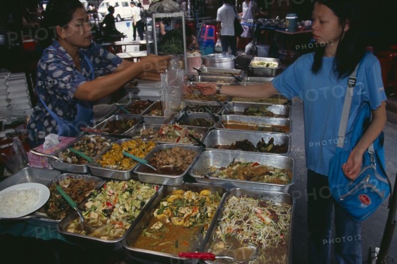 THAILAND, South, Bangkok, Woman selling cooked food to a local woman in an alley beside Patpong 1