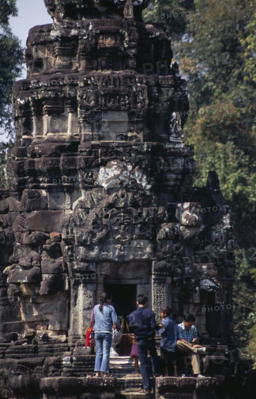 CAMBODIA, Siem Reap Province, Angkor, Neak Pean.  Tourists lighting incense at entrance to small temple on circular terrace.