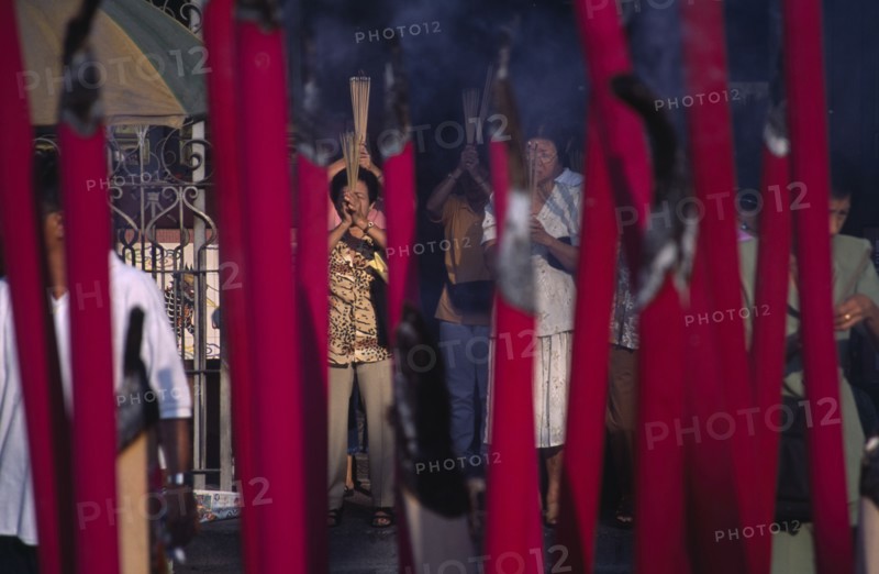MALAYSIA, Penang, Georgetown, Kuan Yin Teng or Temple of Mercy with people carrying jos sticks and  praying in front of large jos sticks