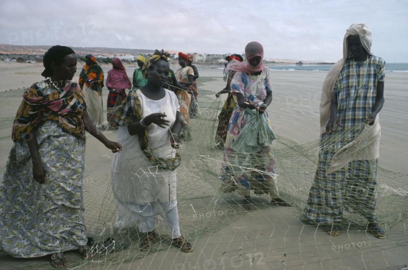 SOMALIA, Industry, Settled nomad women mending fishing net on shore of beach.