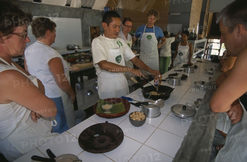 THAILAND, Krabi, Koh Lanta Yai, Cookery class at Time For Lime on Klong Dao beach. Instructor demonstrating the use of a wok to tourists