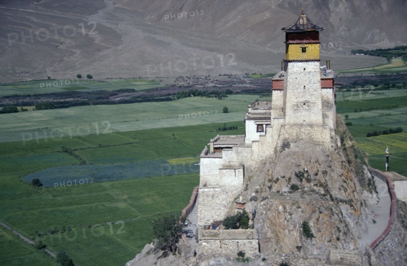TIBET, Jumbulagang, Hilltop monastery with agricultural land and lower mountain slopes spread out below.