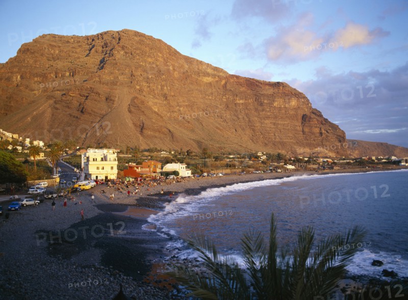 SPAIN, Canary Islands, La Gomera, Valle Gran Rey.  Crowds on black volcanic sand beach at sunset.
