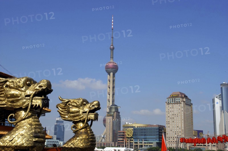 CHINA, Shanghai, City skyline and Television Tower with golden dragon head statues in the foreground