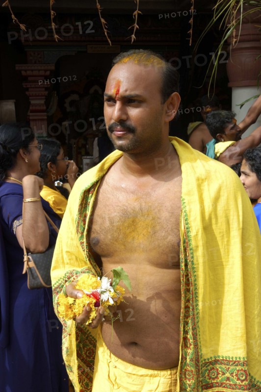 SINGAPORE, , Portrait of a man holding flowers and wearing yellow at an Indian Temple