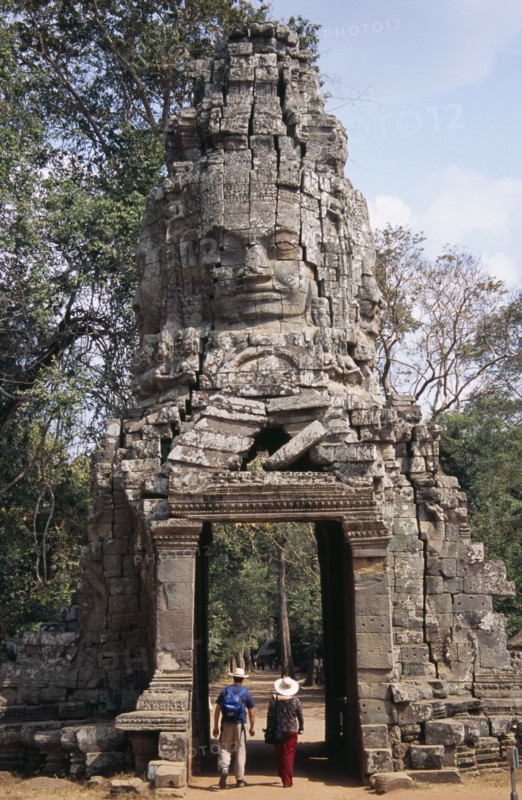 CAMBODIA, Siem Reap, Angkor, Ta Prohm monastic complex with tourists walking through the four faced west gate