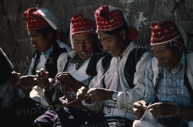 PERU, Puno, Lake Titicaca, Taquile Island.  Line of men knitting.