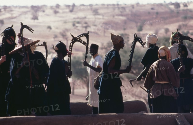 20049655 MALI  People Dogon rooftop dancers brandishing carved wooden staffs a symbol of a particular Dogon fraternity.
