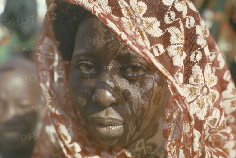 NIGERIA, North East, Maiduguri, Portrait of Kanuri Arab woman with sun through head dress casting shadow patterns across her face.