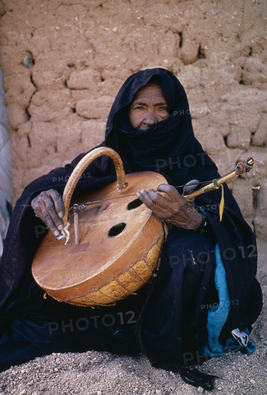 NIGER, Tribal Music, Tuareg woman playing an Imzad.  Traditional instrument consisting of a goatskin covered gourd or wooden resonator played with a curved bow and horsehair string.
