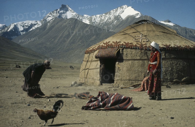 AFGHANISTAN, Nomadic People, Kirghiz nomads shaking out rugs beside yurt.