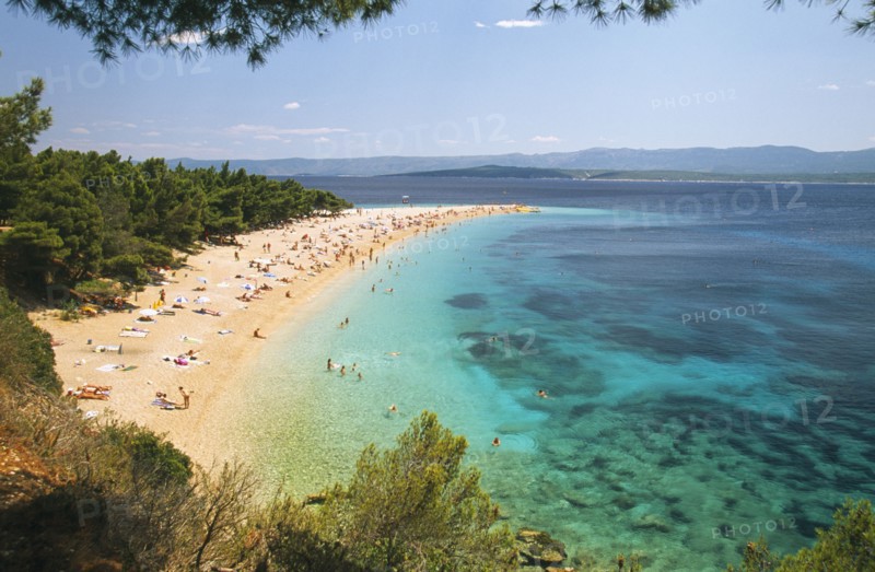 CROATIA, Brac Island, Bol, View over Zlatni Rat Beach lined with trees and scattered bathers