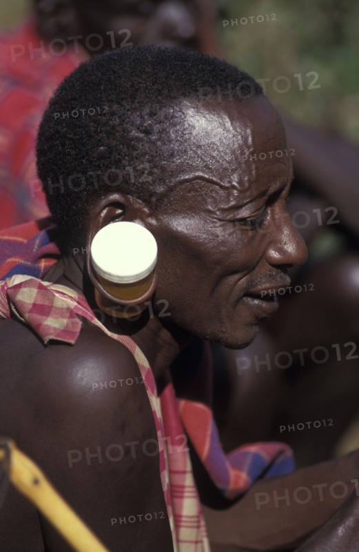 KENYA, , A maasai man at an intiation ceremony for the Moran coming into manhood with ears stretched with a pill container.