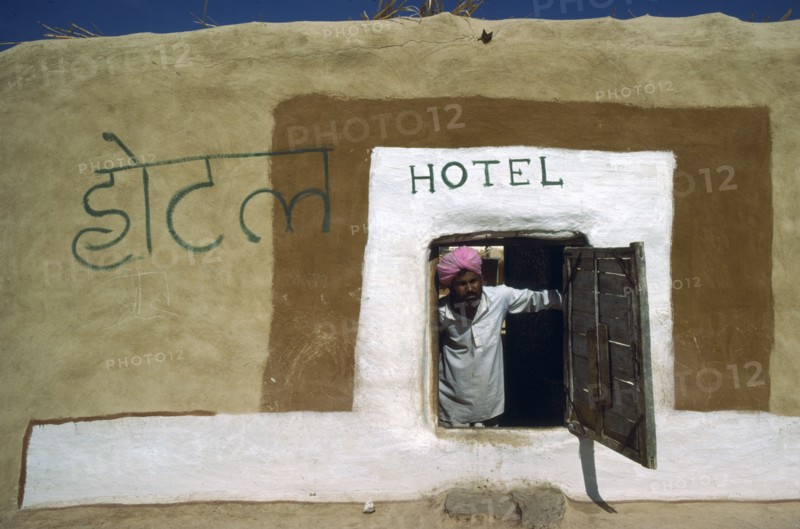 INDIA, Rajasthan, People, Man in turban looking out of low open doorway of village hotel.