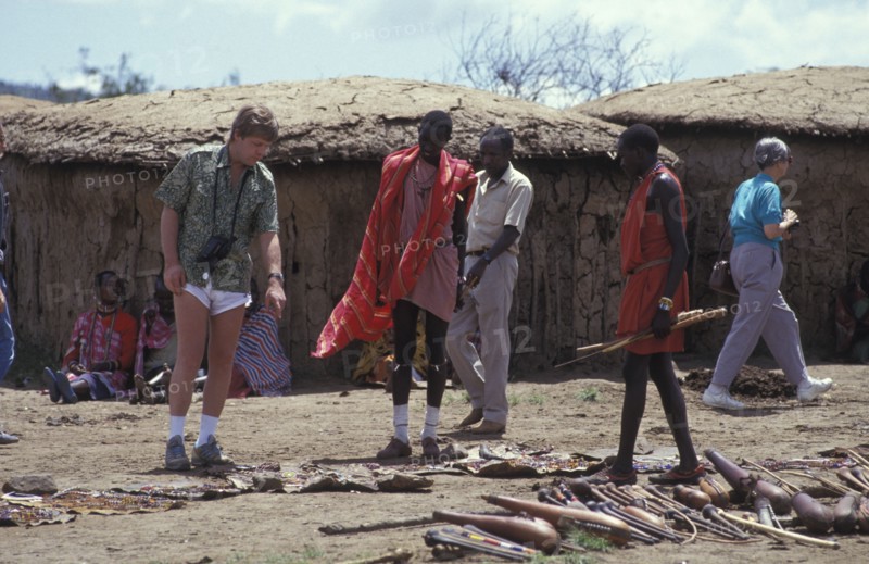 KENYA, , An American tourist haggles with a Maasai man in a cultural manyatta set up to interface the Maasai directly with tourists.