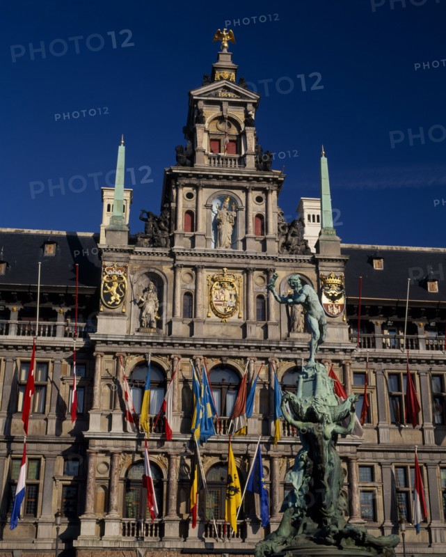 BELGIUM, Flemish Region, Antwerp, Grote Markt or Main Square.  The Brabo Fountain with the Town Hall facade hung with flags behind .
