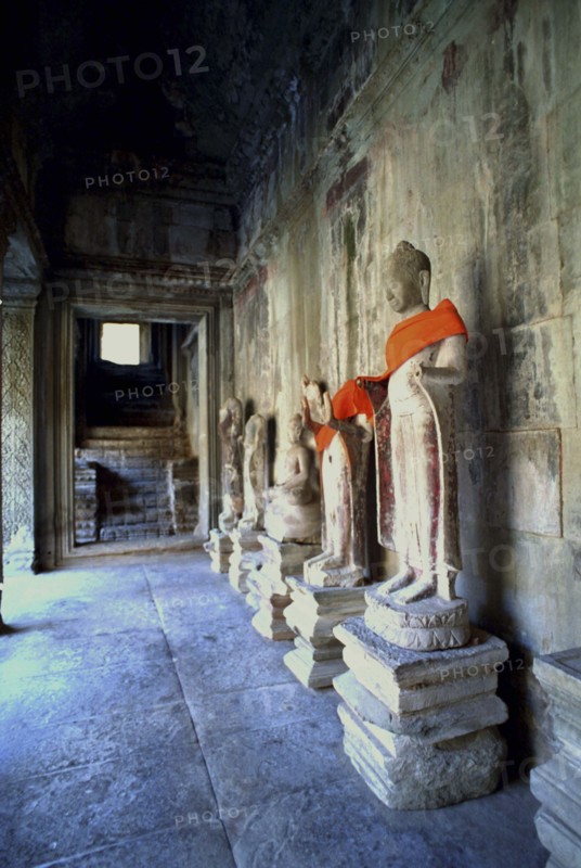 CAMBODIA, Angkor, View along row of Buddha statues draped in orange cloth at Angkor Wat