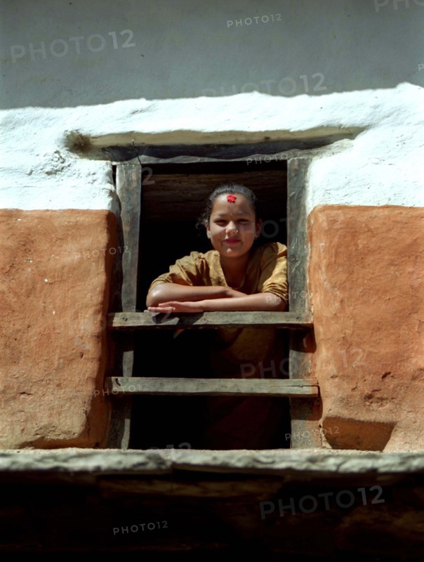 NEPAL, Tatopani Village, Girl framed by her wooden window