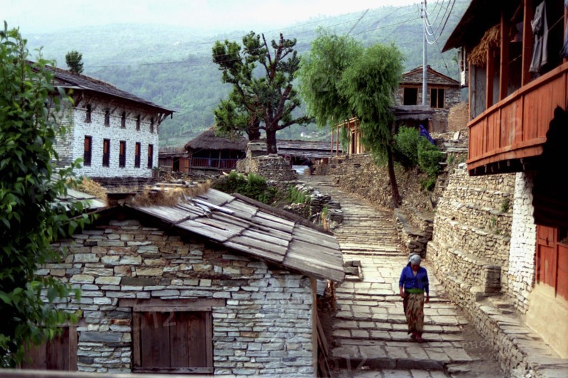 NEPAL, Ghorapani Village, View of the village with woman walking down a cobbled street