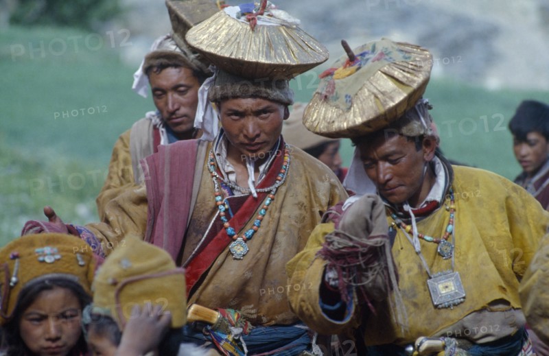 INDIA, Zanskar, Men in gold head dresses who stage a mock abduction to take bridegroom to meet bride in traditional Buddhist wedding ceremony.