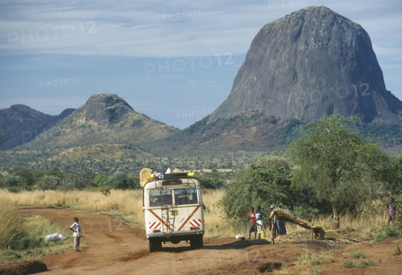 UGANDA, Karamoja, Minibus travelling along dirt road with people at the side