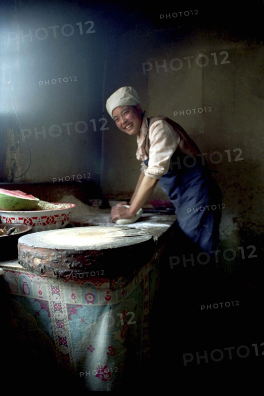 CHINA, Gansu, Langmusi, Smiling cook rolling pastry for an Apple Pie