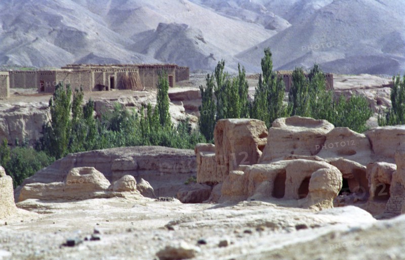 CHINA, Xinjiang, Turpan, View over the Ancient ruins in desert landscape toward distant buildings