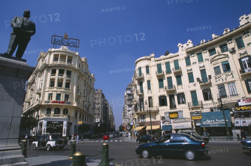EGYPT, Cairo , Midan Talaat Harb.  Traffic on city road lined by cream coloured buildings with green shutters and curved facades