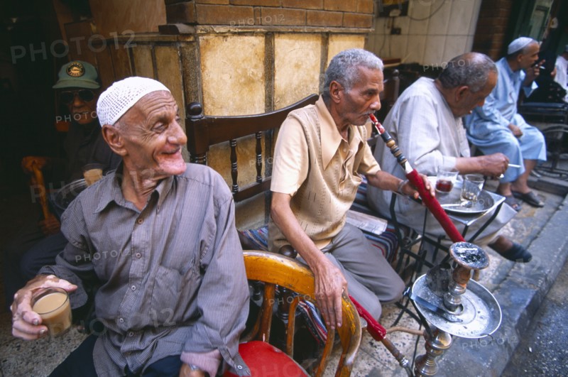 EGYPT, Cairo , Group of men smoking sheesha water pipes and drinking tea in an ahwa or coffee house.