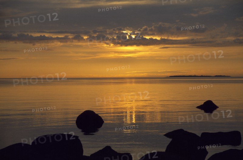 ESTONIA, Sunset, Sunset over water with rocks in the foreground on the longest day of the year