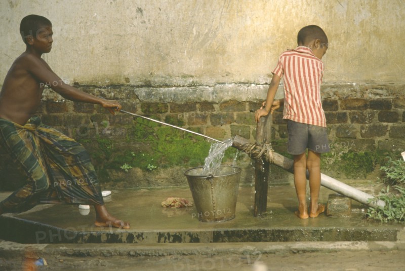 BANGLADESH, Chittagong, Shamshangar, Two young boys drawing water from rowerpump.