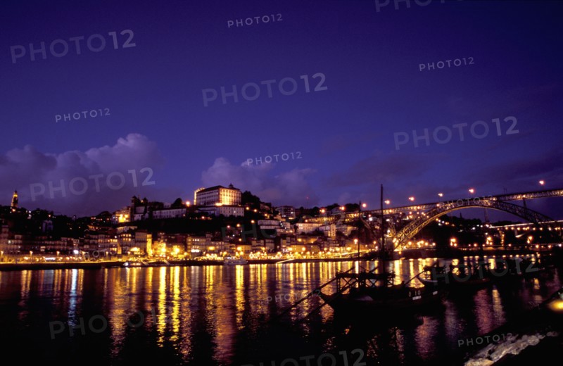 PORTUGAL, Porto, Oporto, View over silhouetted boats moored in the port toward the city illuminated at dusk