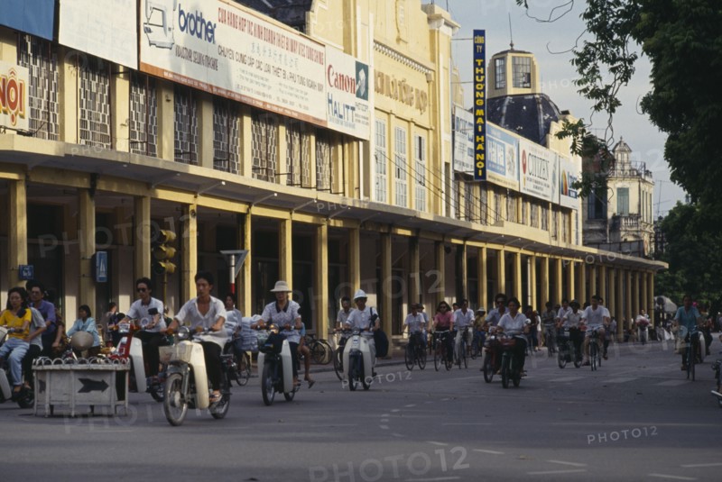 VIETNAM, North, Hanoi, Mopeds in a street lined with colonnaded buildings